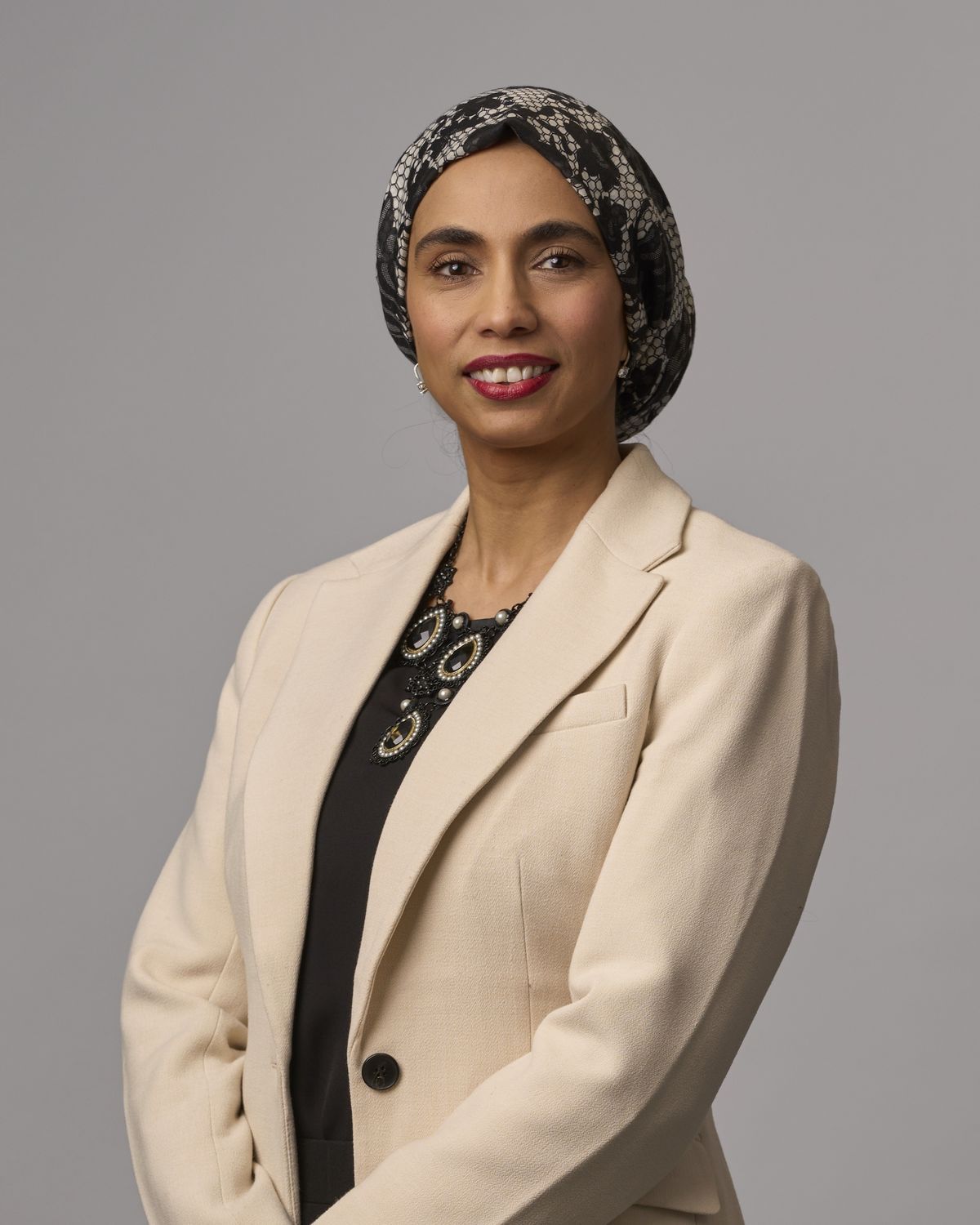 Corporate headshot of a professional woman in a cream blazer and headscarf