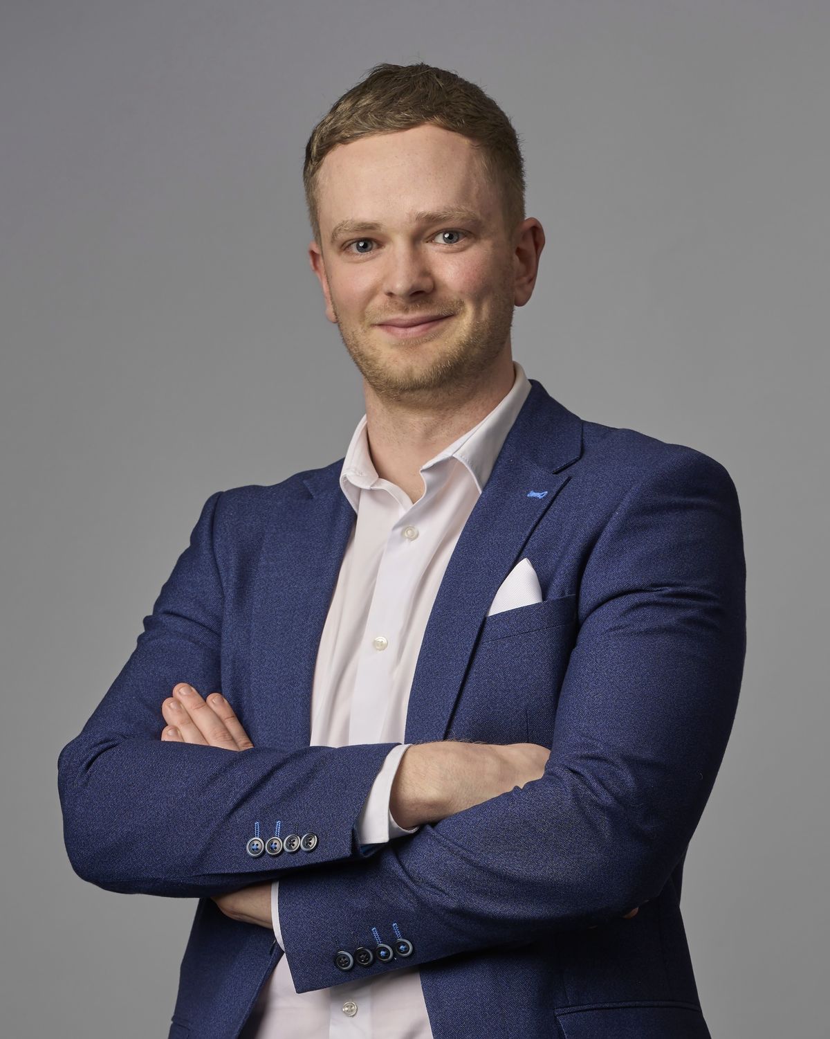 Corporate headshot of a young professional man in a blue blazer