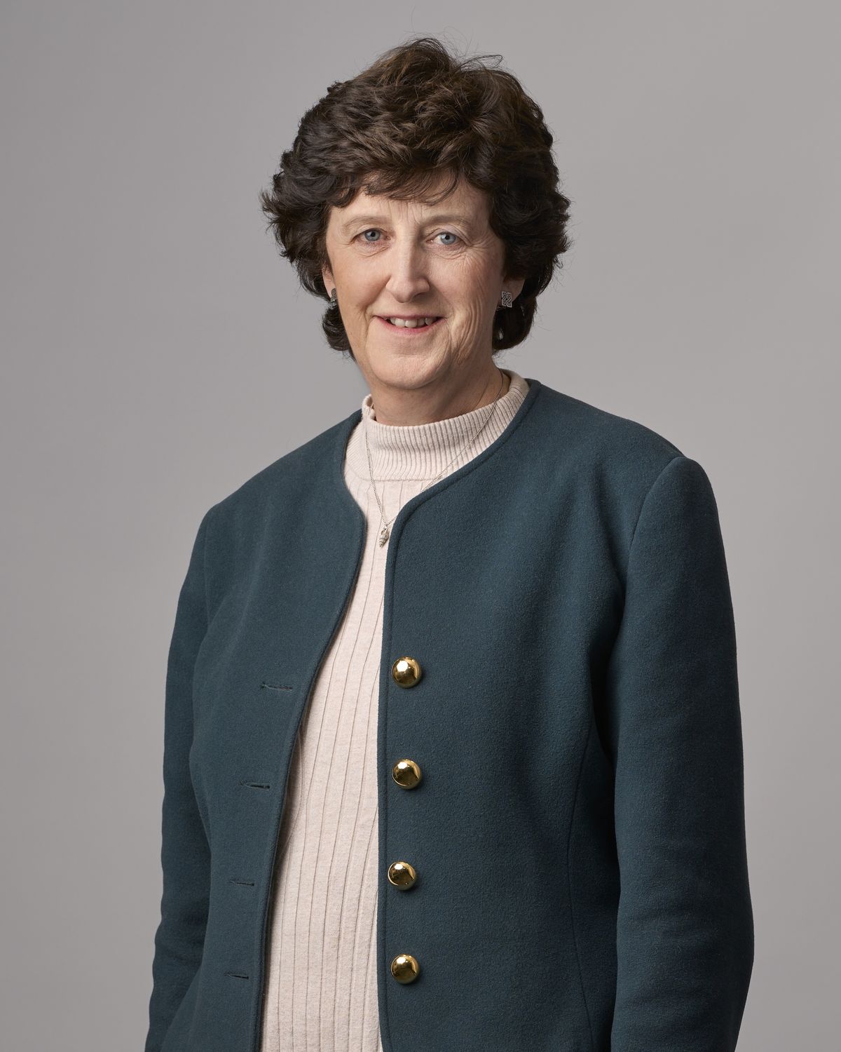 Corporate headshot of an experienced professional woman in a teal jacket