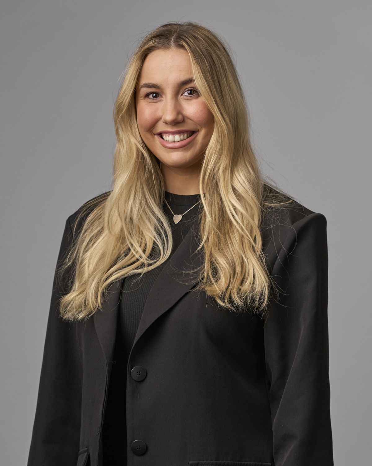 Corporate headshot of a smiling professional woman in an oversized black blazer