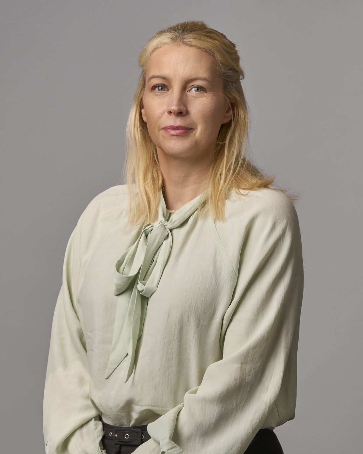 Corporate headshot of a professional woman in a sage-green blouse