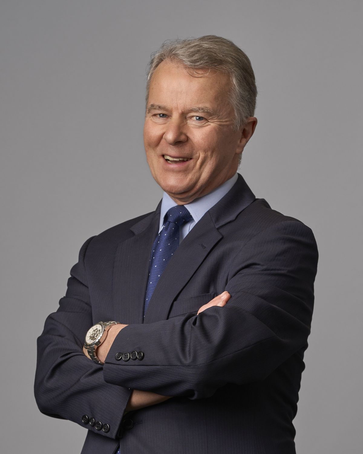 Corporate headshot of a senior professional man in a navy suit and tie, taken by Manchester Headshots